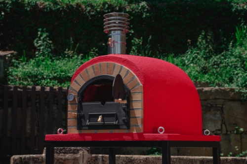 Four à pizza bois REAL 100 cm rouge installé dans un jardin