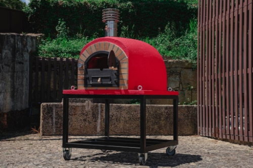 Four à bois REAL 120 cm rouge installé en extérieur pour cuisson au feu de bois